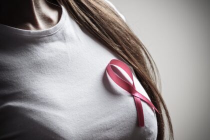 Kobieta trzymająca różową wstążkę – symbol walki z rakiem piersi