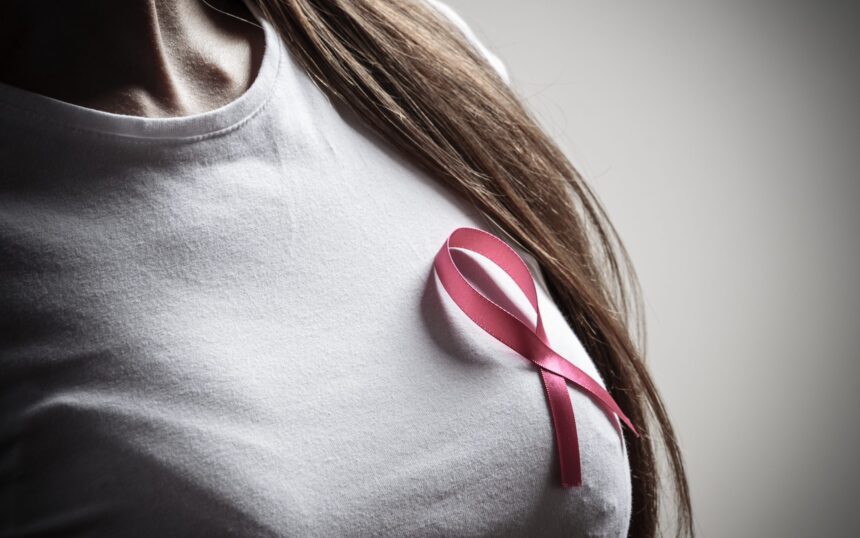 Kobieta trzymająca różową wstążkę – symbol walki z rakiem piersi