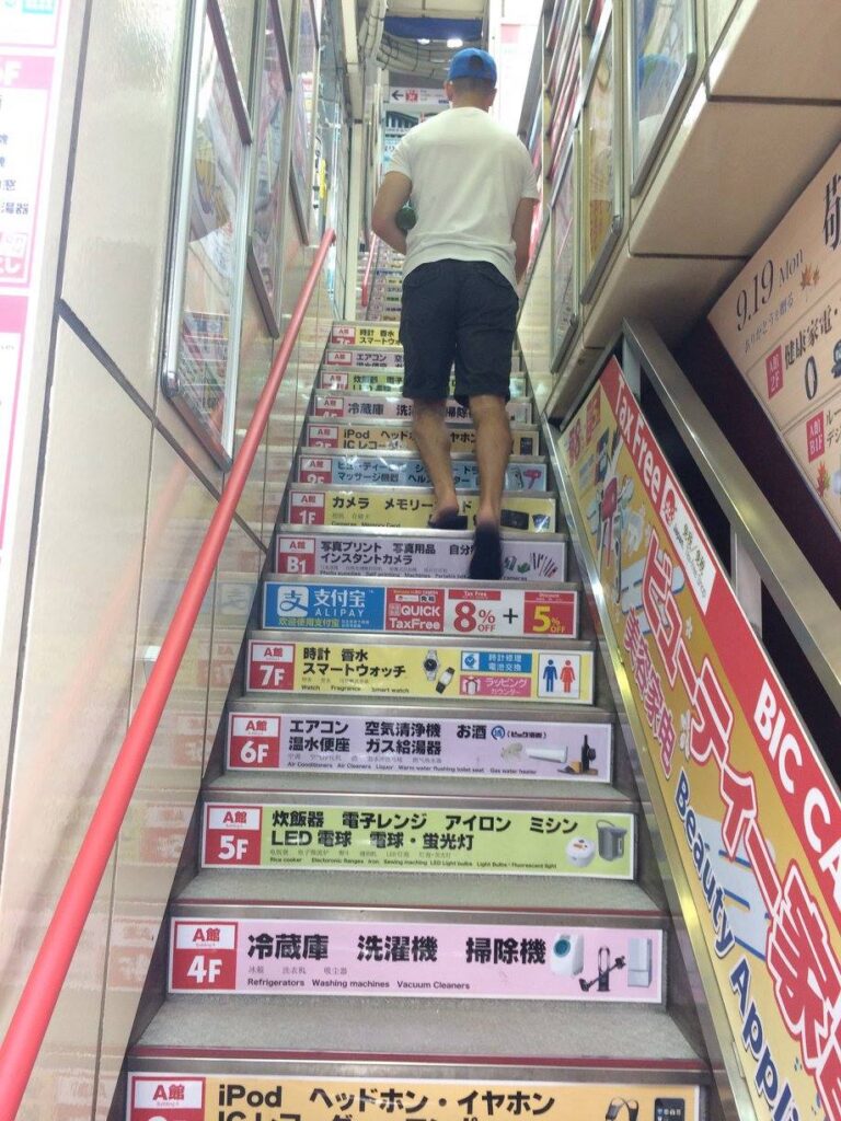 Schody w sklepie elektronicznym w Akihabara, Tokio – kolorowe reklamy i napisy z ofertą sprzętu elektronicznego.