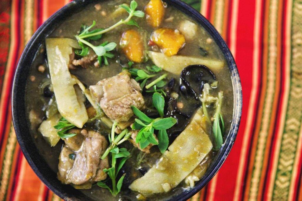 Gęsta laotańska zupa z trawą cytrynową, świeżymi ziołami, warzywami i kawałkami mięsa, podana w tradycyjnej misce