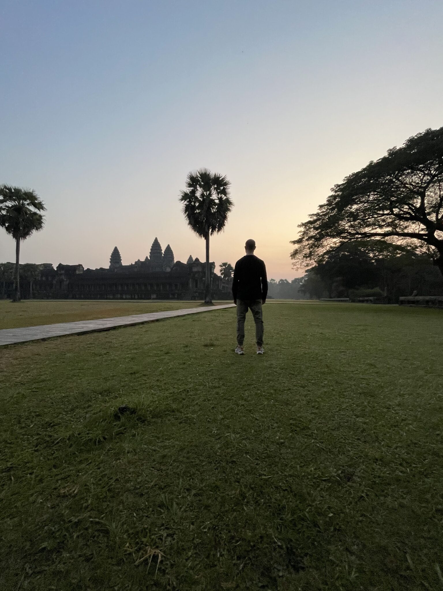 Mężczyzna stojący o świcie przed Angkor Wat w Siem Reap – slow travel i refleksja nad chorobą